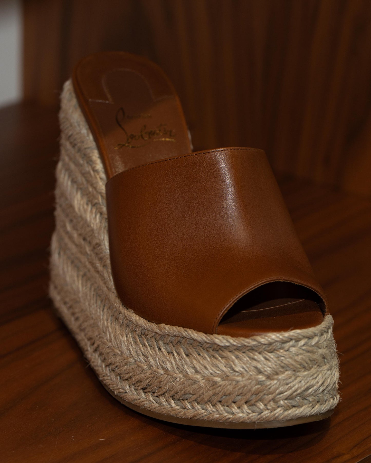 Brown wedge sandal with jute sole on a wooden surface