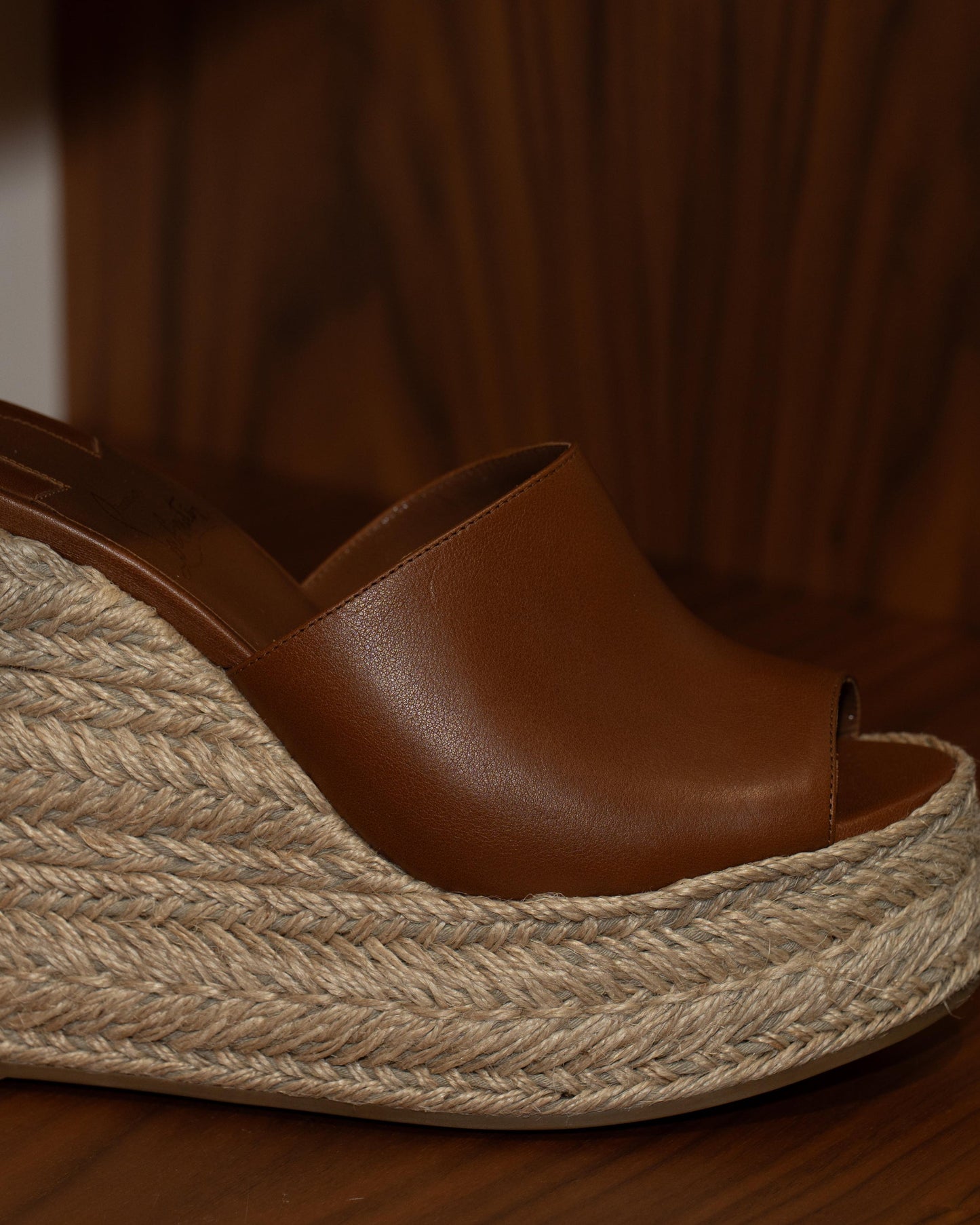 Brown wedge sandal with jute sole on a wooden surface