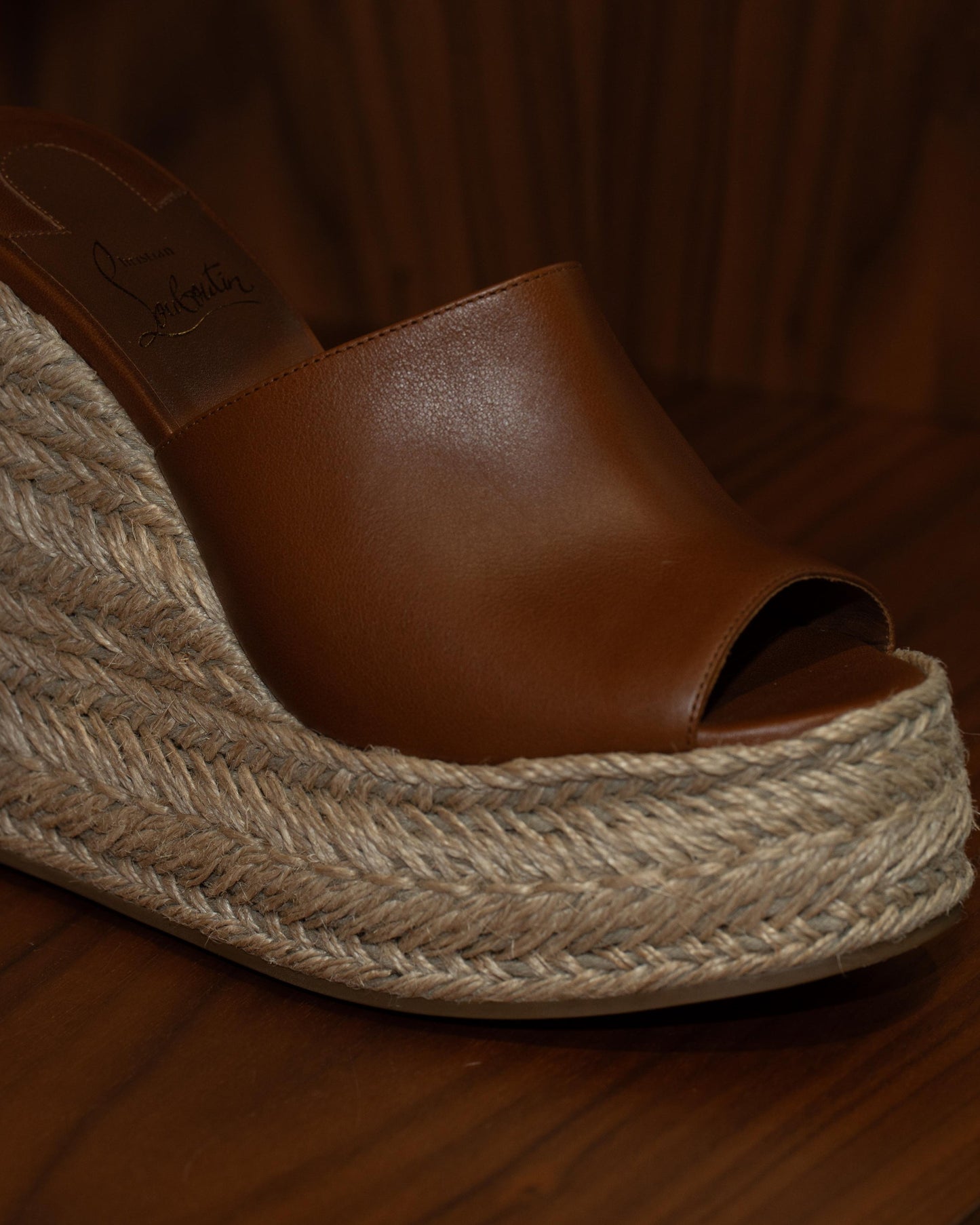 Brown wedge sandal with jute sole on a wooden floor